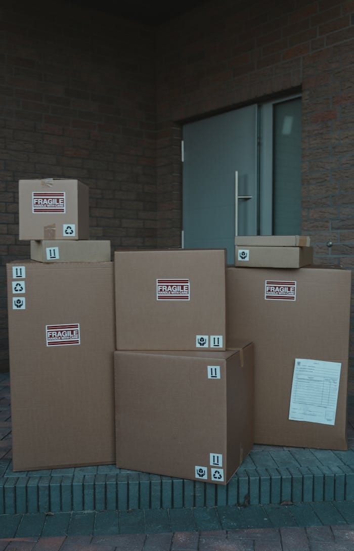 A stack of labeled cardboard boxes piled in front of a closed industrial door, symbolizing delivery service.